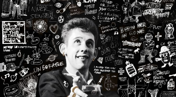 Cover art for 20th Century Paddy – The Songs of Shane MacGowan: a young Shane MacGowan holding a glass against a black wall of white doodles and lyrics